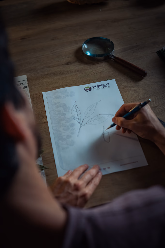 Profissional da Trópicos Consultoria desenha projeto de manejo e conservação ambiental em documento técnico.